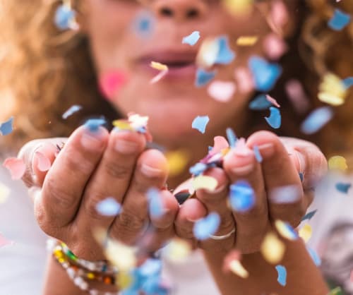 Kvinna blåser konfetti mot kameran. Dubbel bonus på ICA med våra kort.