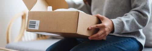 Kvinnar öppnar en låda hon beställt på nätet.