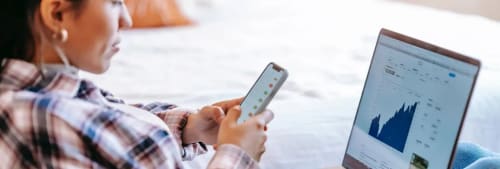 Kvinna tittar på en mobil och en dator