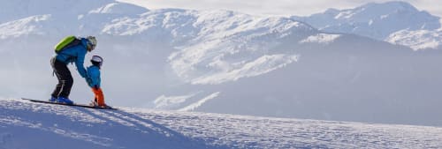 Pappa lär ett barn åka slalom.