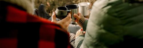 Två personer skålar i termismuggar. Därför ska ni skriva samboavtal.