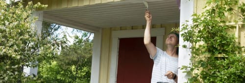 Man som målar om sitt hus. Nya bygglovsregler gäller från december 2025