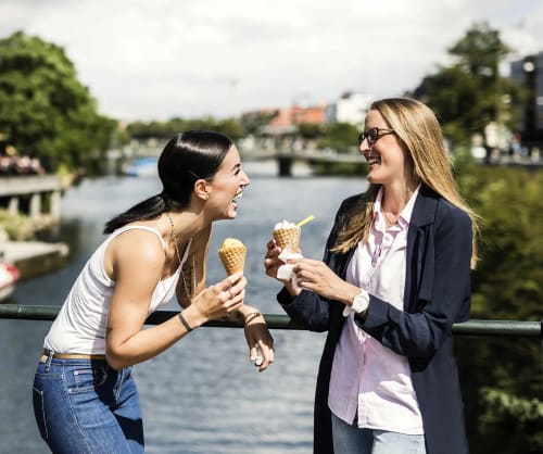 Två skrattande kvinnor som äter glass. Fördelar att vara kund i ICA Banken.