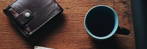plånbok och kaffe på ett bord. Höjt barnbidrag 2018.