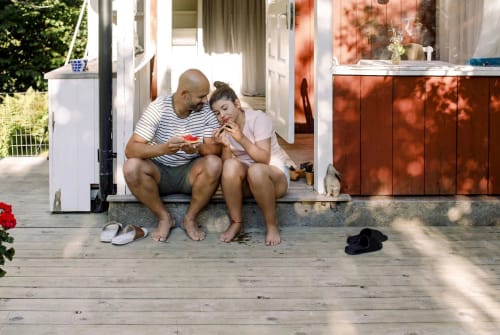 Pappa och tonårsdotter sitter och äter melon vid sitt fritidshus.