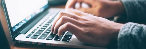 Handla säkert på nätet. Två händer som skriver på ett datortangentbord.