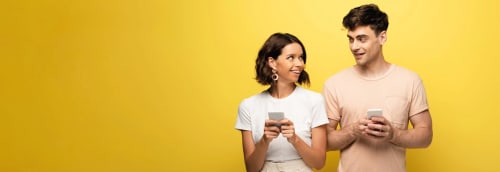 Tjej och kille med varsin mobiltelefon