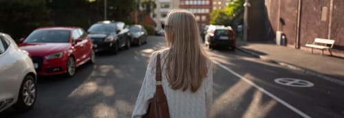 Kvinna promenerar på en gata i en stad med ryggen mot betraktaren