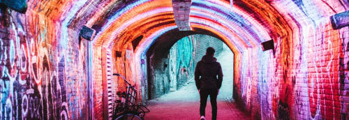 Man går i tunnel med graffitimålningar