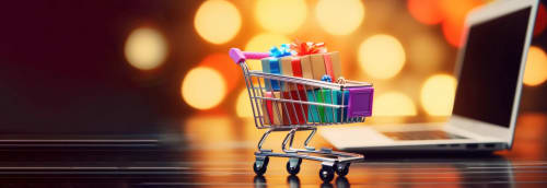 En kundvagn med julklappar i miniatyr framför en laptop