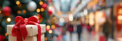 Julklapp med en julgran i bakgrunden i ett shoppingcentrum.