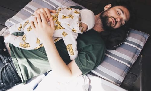 Pappa som sover med sin baby på bröstet.