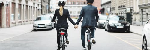 Ett par som cyklar och håller varandras händer.