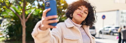 Ung kvinna ler mot sin smartphone och tar en selfie