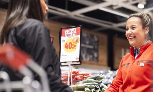 En anställd i en ICA-butik som talar med en kund.