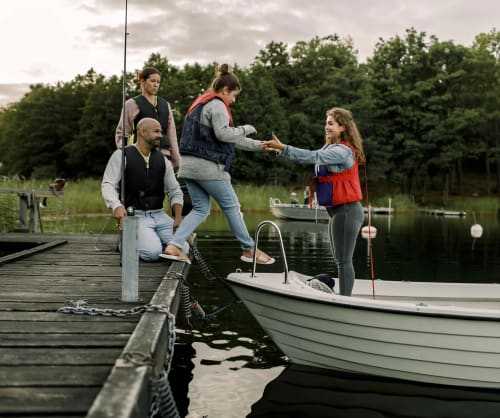 Familj som håller på att kliva ned i en båt för att åka ut och fiska. Låna till köp av ny båt hos ICA Banken.