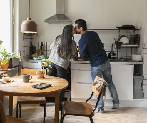 Par som står i köket och pussar varandra. Samla lånen hos ICA Banken och få pengar över till annat.