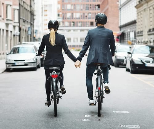 Ett par cyklar på en gata och håller varandra i hand.