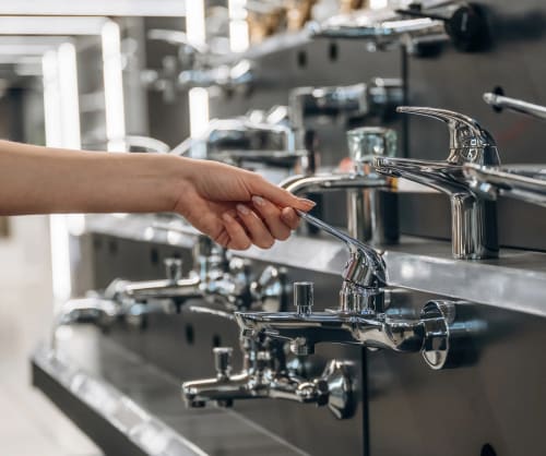 Person som provar kranar i en byggvaruhandel. Lån till nytt badrum hos ICA Banken.