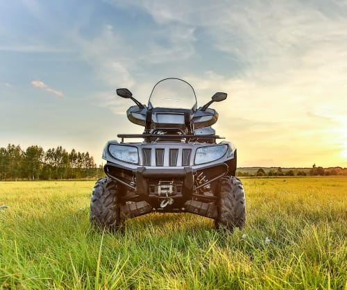 En ATV (fyrhjuling) som står på en äng. Låna till fyhjuling med ICA Bankens ATV lån.