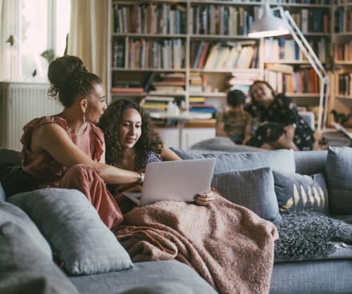 Mamma och dotter i en soffan tittandes på en dator.