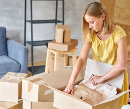 Kvinna packar flyttlådor. ICA Bankens övryggningslån för dig som köpt bostad och valt ICA Bankens bolån.