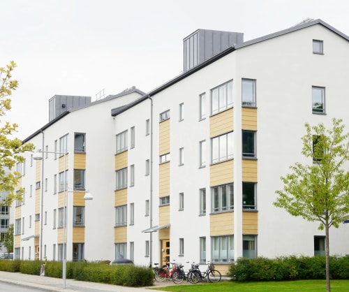 Flerfamiljshus utmed en gata. Låna till bostadsrätt med vårt bostadsrättslån.