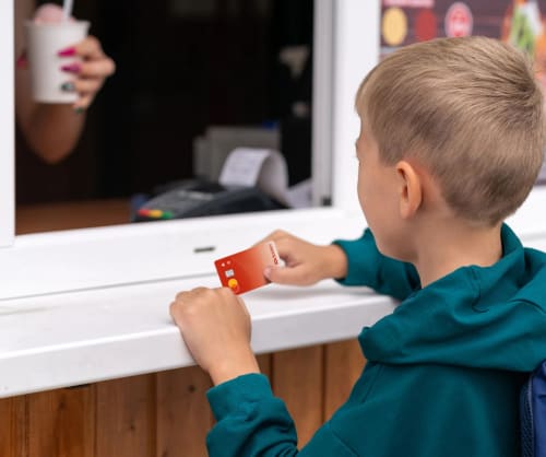 Liten kille betalar med Bankkort Barn och ungdom i en kiosk.
