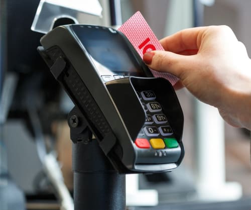 Person betalar med ICA-kort genom att dra det i en betalterminal i en butik.