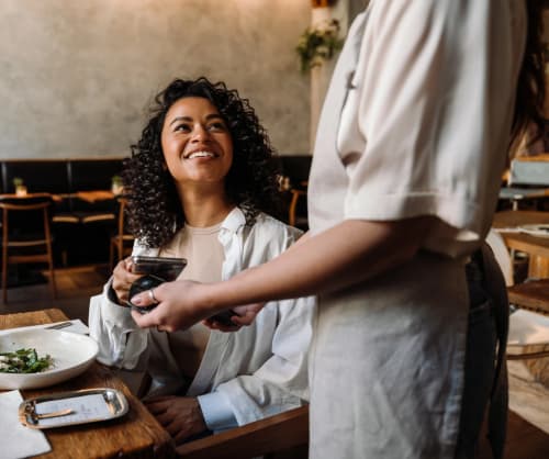 Kvinna betalar med sin smartphone på en restaurang.