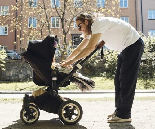 Pappa ute på promenad med en barnvagn.