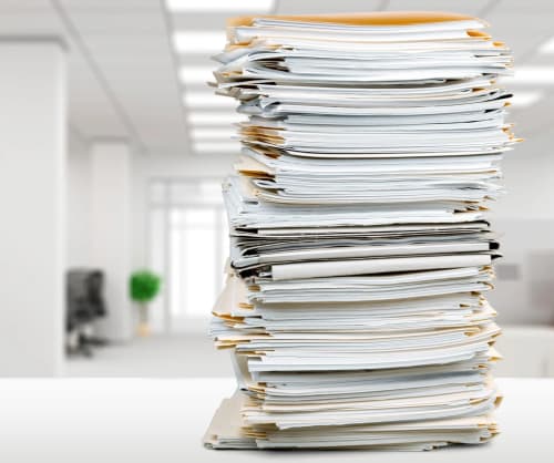 Hög av papper på ett bord. ICA Bankens samtliga villkor för våra produkter och tjänster.