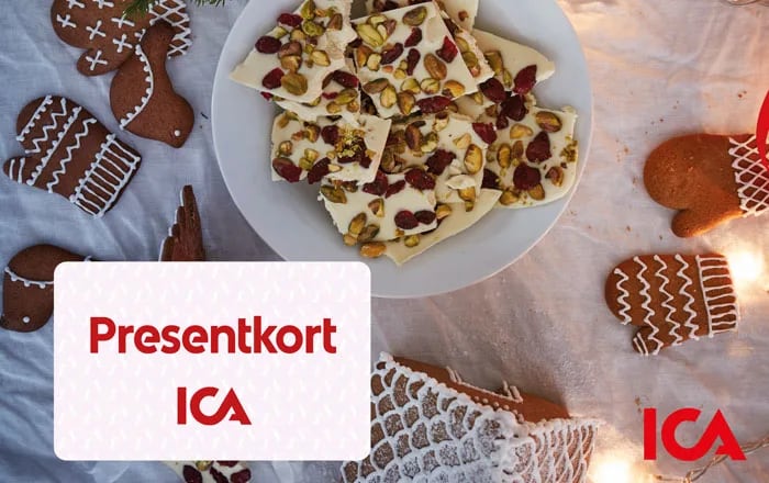 Ett ICA Presentkort mot en julig bakgrund med kakor och godis.