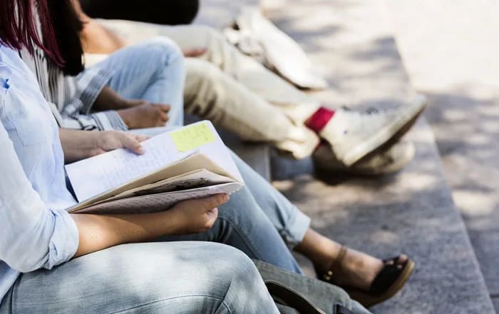 Studenter på rad med böcker i knät.