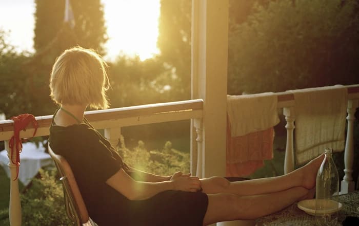 Kvinna sitter på en veranda i kvällssolen.