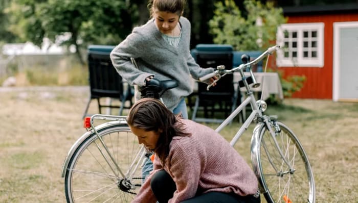 Mamma hjälper dottern med cykeln.