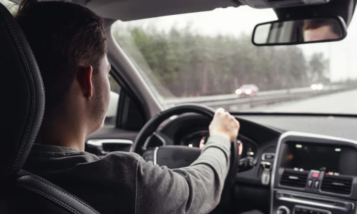 Man som kör bil på en motorväg.