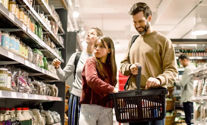 En familj med en mamma, pappa och en dotter som handlar mat i en mataffär.
