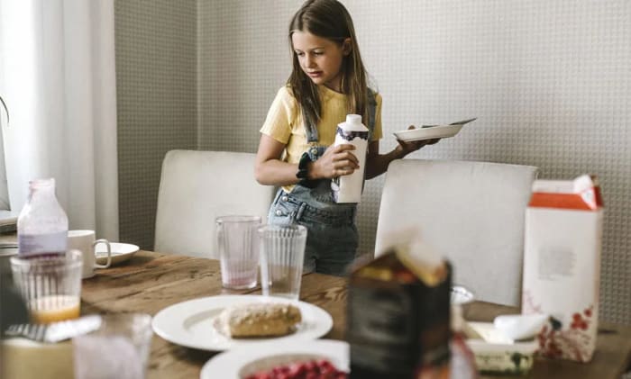 Tjej som dukar av ett bord.