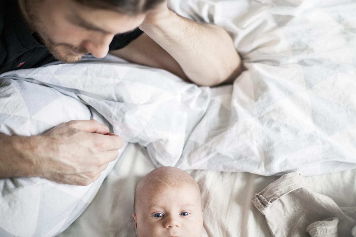 Pappa ligger i sängen och tittar på sin bebis