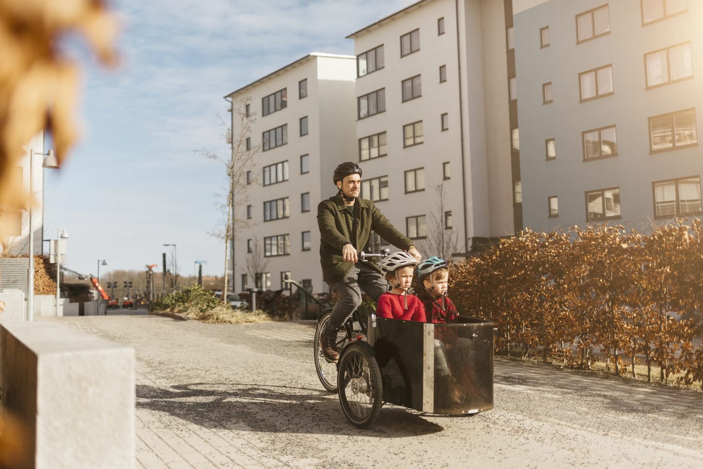 Man cyklar tillsammans med sina barn nedför gatan