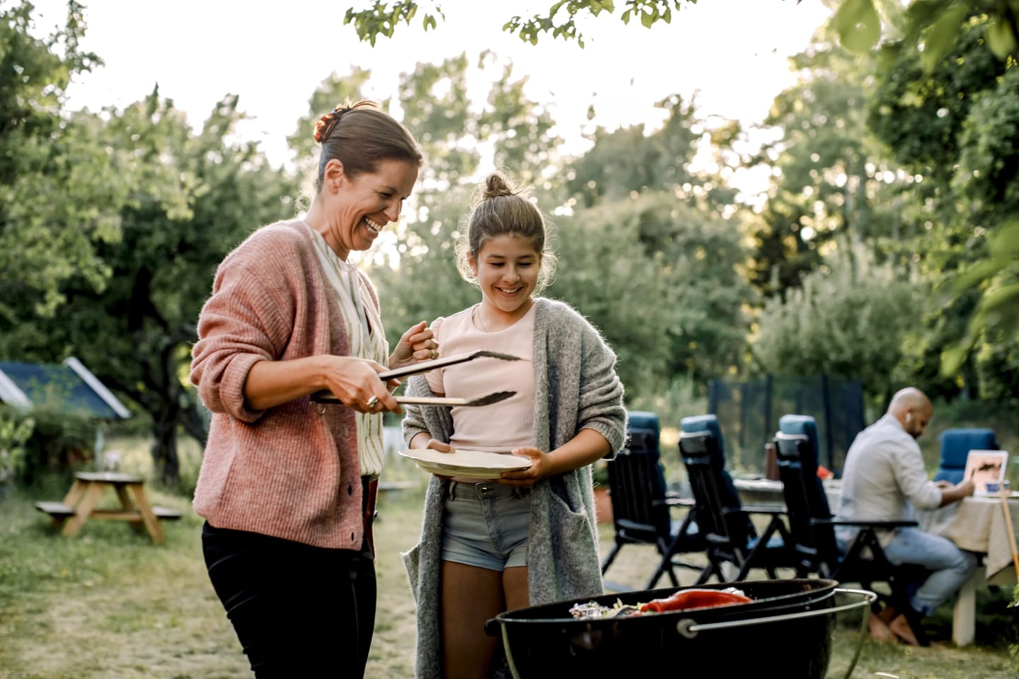 Två tjejer står och pratar och ler samtidigt som de grillar.