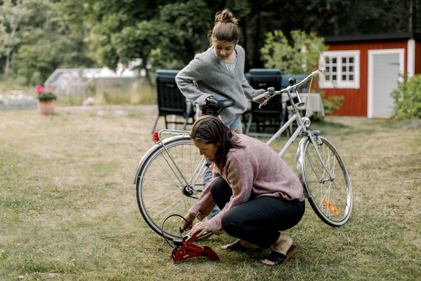 Mamma pumpar cykeln till sin dotter som står bredvid.