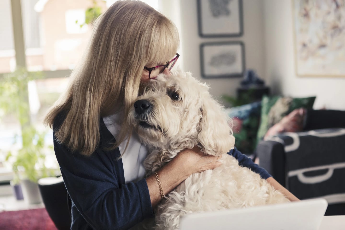 Närbild på en kvinna som sitter med sin hund i knät och gosar.