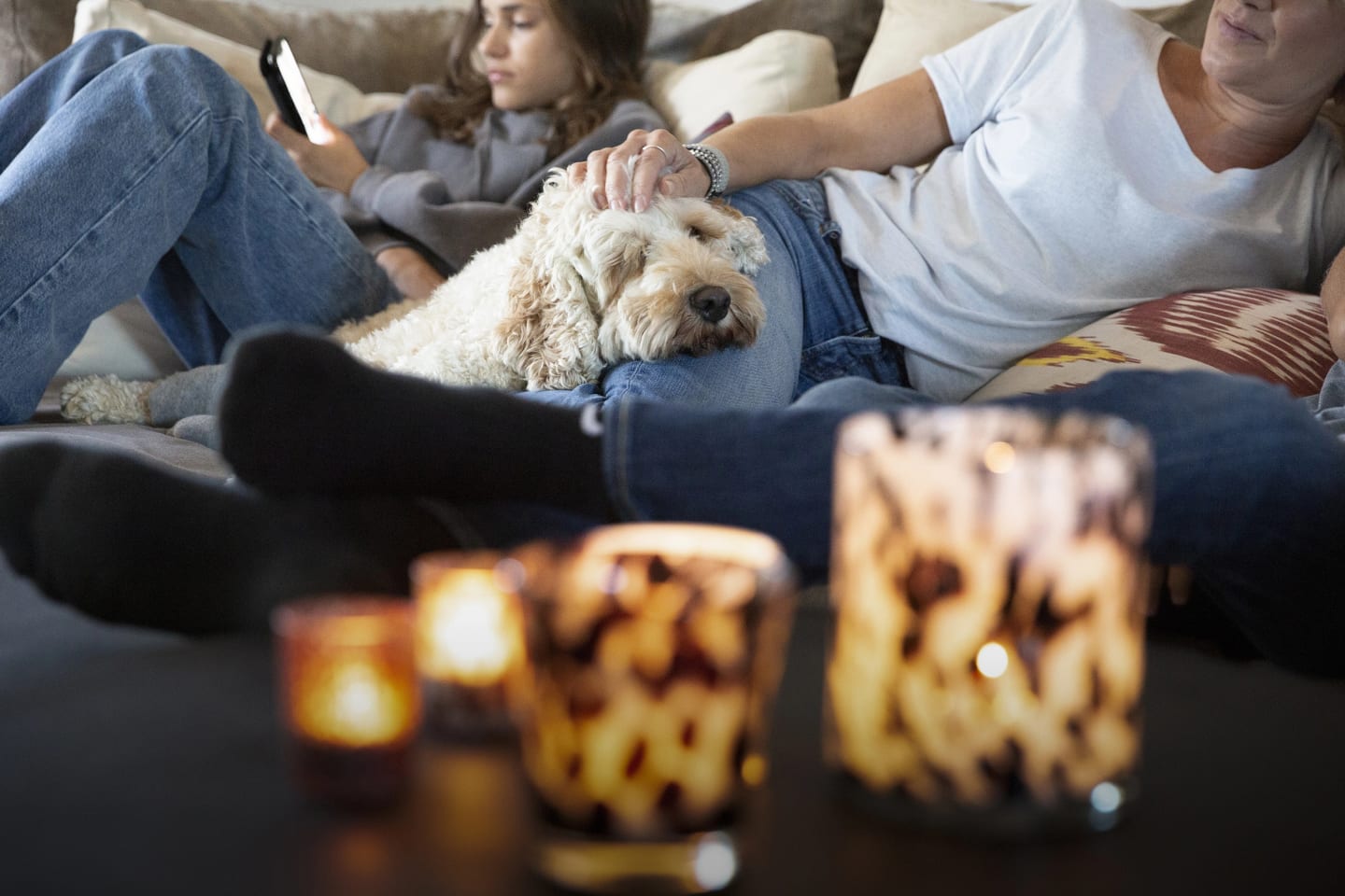 Familj sitter i soffa och myser, hunden ligger mellan mamma och dotter och vilar.