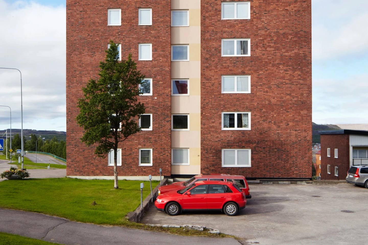 Bild på flera bilar som är parkerade utanför ett höghus.