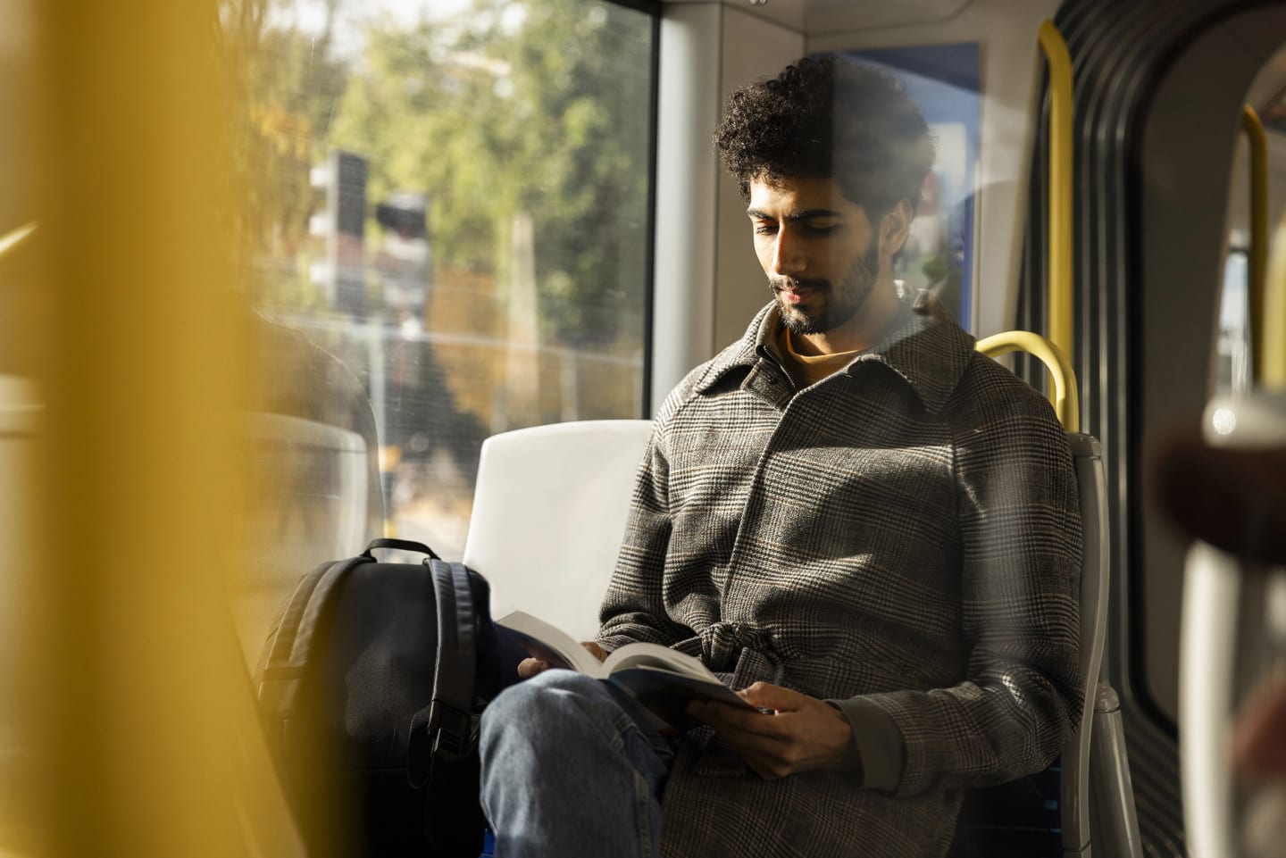En bild på en man som läser en bok på bussen.