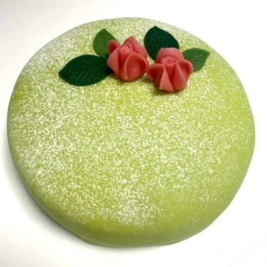 Grön prinsesstårta med ros och blad på toppen