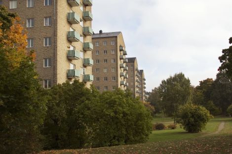 Flera lägenhetshus bredvid varandra utmed en park.