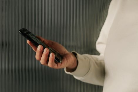 Kvinna håller mobil i sin hand och kollar besked på sin kreditupplysning